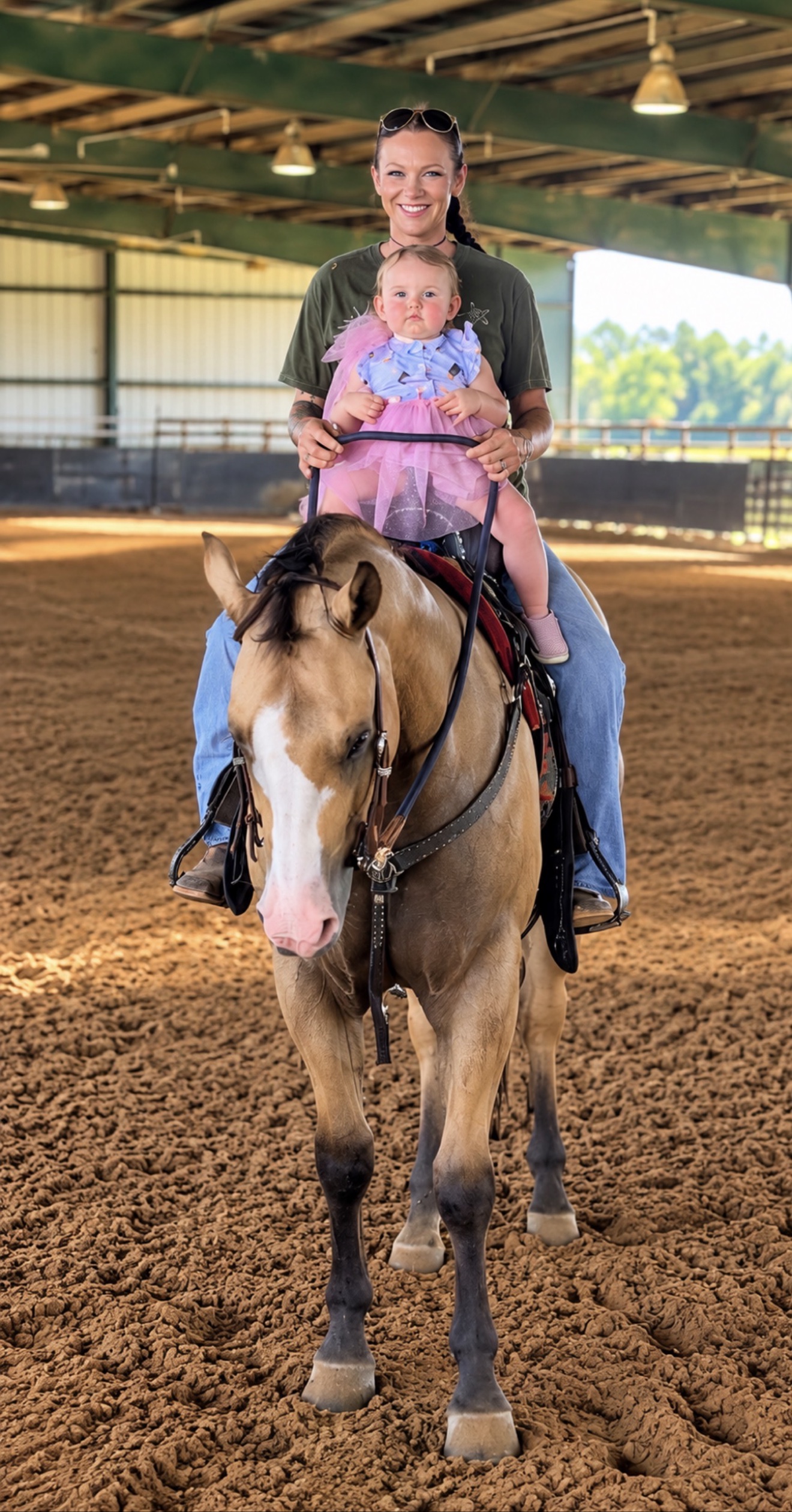 Hayley riding a horse with a child in an indoor arena